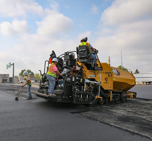 Paver laying hot asphalt onto a commercial parking lot.