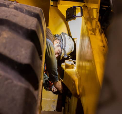 hard hat and headlamp is repairing or inspecting machinery
