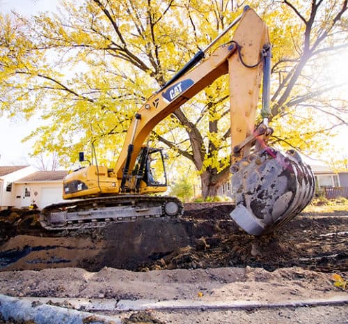 CAT Excavator next to underground utility trench.