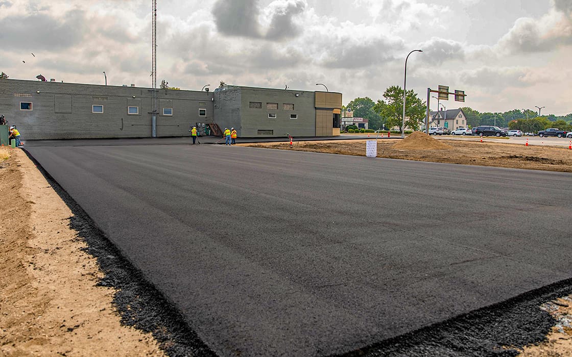 New commercial asphalt parking lot with Youth for Christ building in the background.