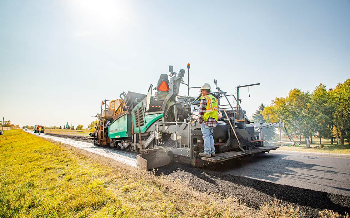 Screed operator standing on paver.