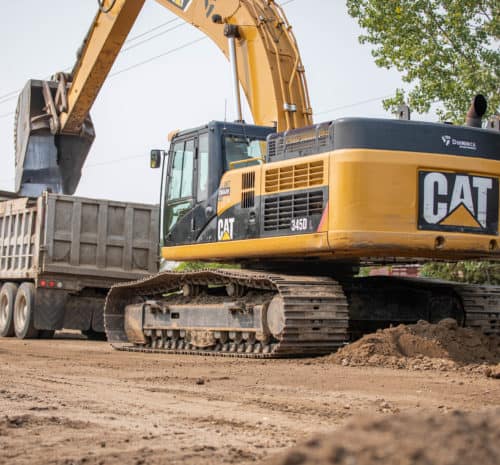 Loader removing dirt from tandem truck on a grading site.