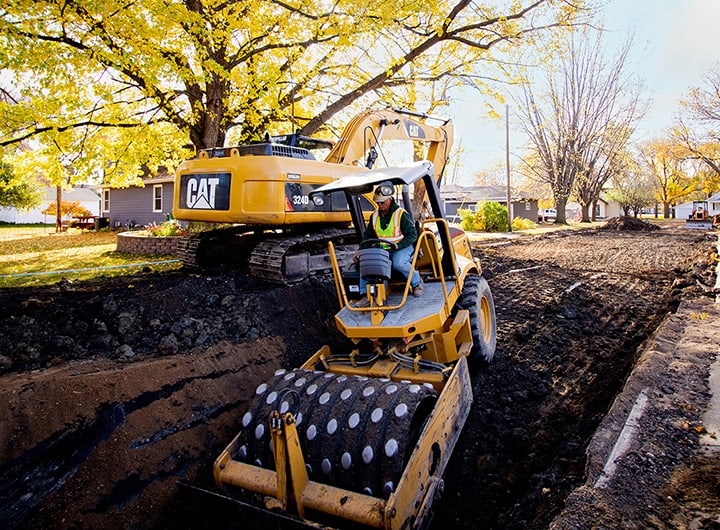 Sheepsfoot roller compacting soil on underground project.