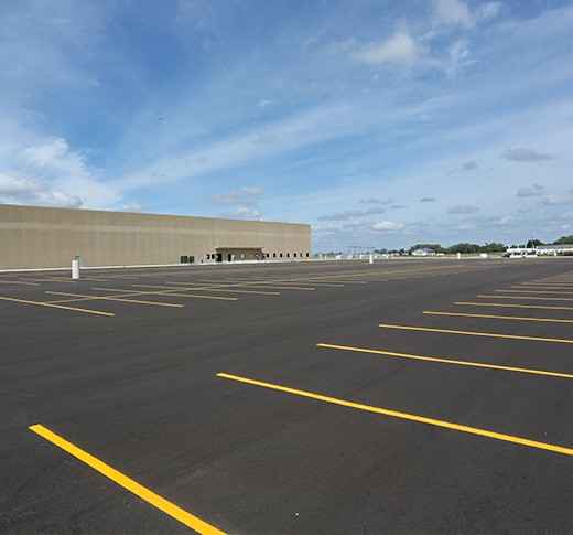 New asphalt parking lot with large FedEx building in the background