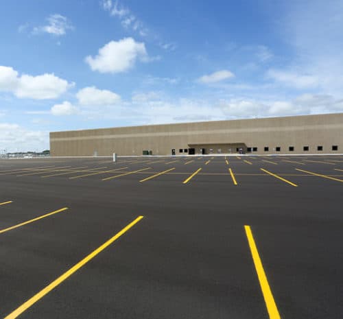 New asphalt parking lot with large FedEx building in the background
