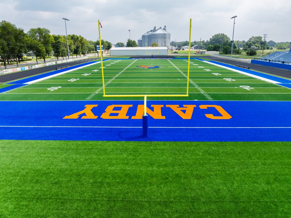 Modern high school football field with blue end zones and goalposts
