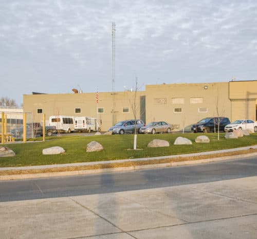 A small, building with several parked cars and a white van in front - 2021