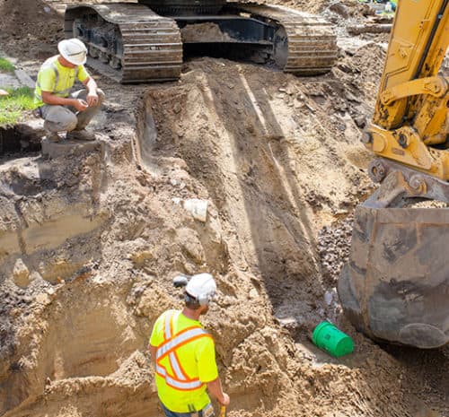 One man kneeling overtop a trench.
