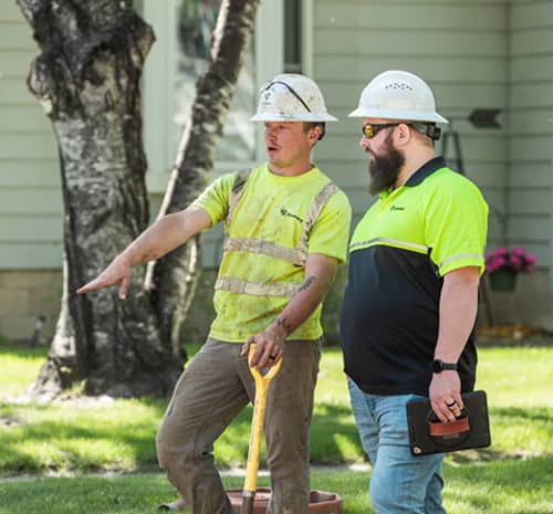 Two men in safety vests and hard hats near construction site. - August 2022