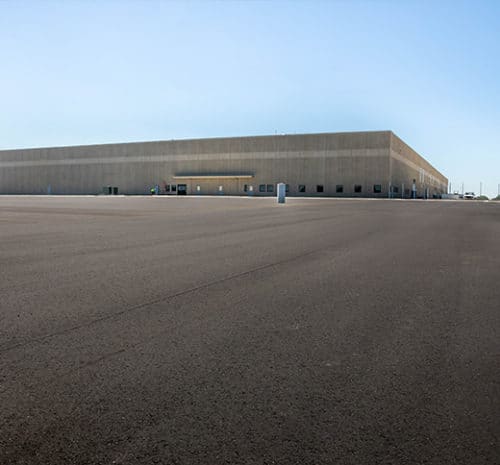 New asphalt parking lot with large FedEx building in the background