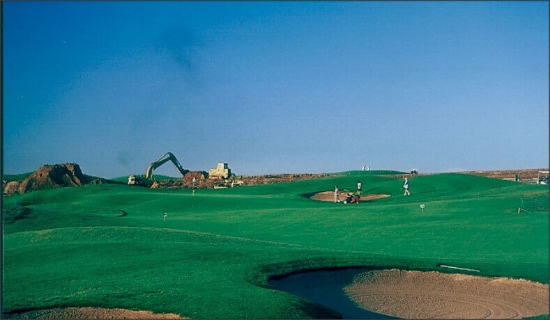 Golf course with golfers and construction in the background